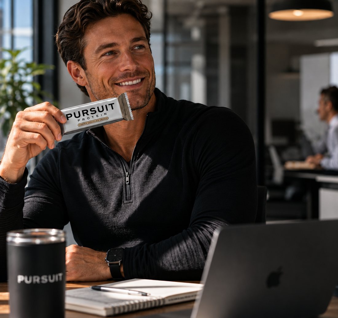 Chris B. holding a Pursuit Protein bar at his desk